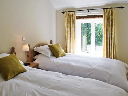 two beds in a room with a window at Bank Cottage in Grindleford Bridge