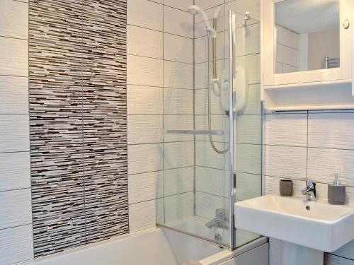 uma casa de banho com uma cabina de duche em vidro e um lavatório. em Honey Cottage em Auchnarrow