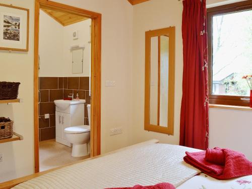 a bedroom with a bed and a toilet and a window at Rowanburn Lodge in Ellonby