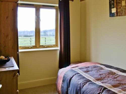 a bedroom with a bed and a window at Buttercup Cottage in Ripley