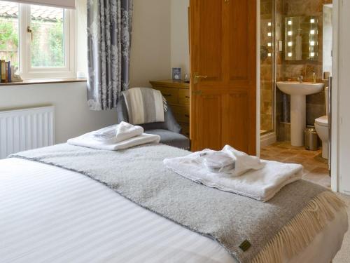 a bedroom with a bed with towels on it at Newstead Cottage in Thornton Dale