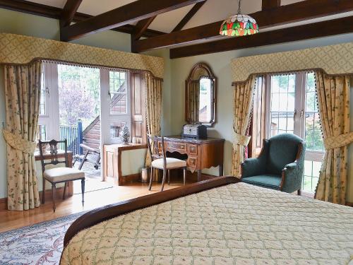 een slaapkamer met een bed, een bureau en stoelen bij Dove Cote House in Westleigh
