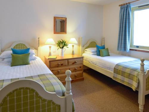 a bedroom with two beds and a window at Cluny in Aberfeldy