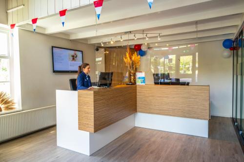a woman standing at a reception desk in a office at Comfort Rooms by EuroParcs Buitenhuizen in Velsen-Zuid