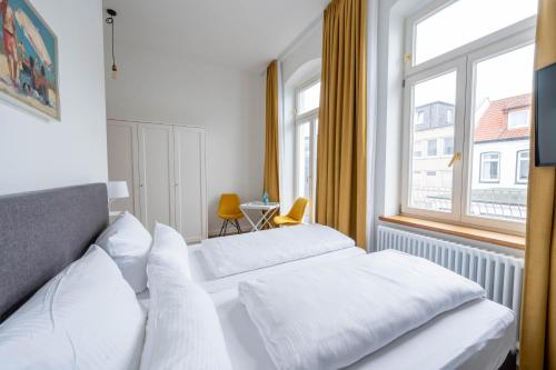 two beds in a hotel room with a window at Logierhaus am Rathaus in Norderney
