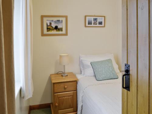 um quarto com uma cama e uma mesa de cabeceira com um candeeiro em Rose Cottage - W41462 em Sturminster Newton