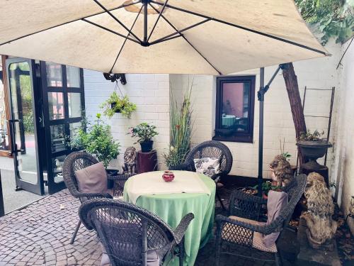 une terrasse avec une table, des chaises et un parasol dans l'établissement Hotel Brunnenhof, à Bad Nauheim