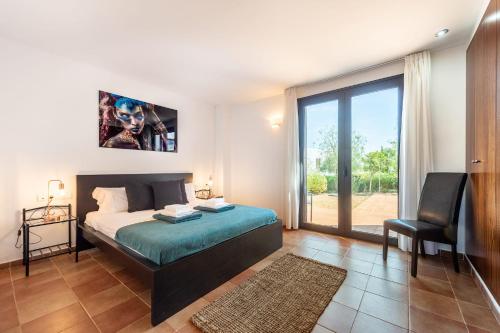 um quarto com uma cama, uma cadeira e uma janela em Can Terra con piscina em Sant Josep de sa Talaia