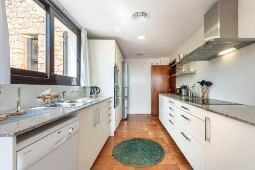 uma cozinha com armários brancos e um tapete verde em Can Terra con piscina em Sant Josep de sa Talaia