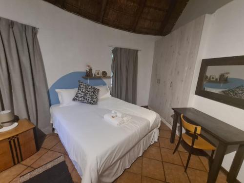 1 dormitorio con cama, mesa y espejo en Mountain Villa House, en Hartbeespoort