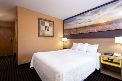 a hotel room with a white bed and a painting on the wall at Days Inn by Wyndham Anderson IN in Anderson