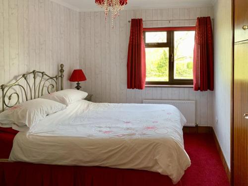a bedroom with a white bed with a red carpet at Field House in Baschurch