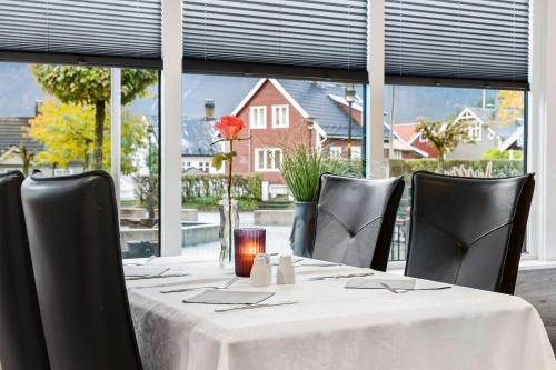 a table with a white table cloth and black chairs and a window at Best Western Laegreid Hotell in Sogndal