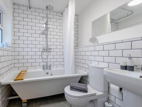 ein weißes Badezimmer mit einer Badewanne, einem WC und einem Waschbecken in der Unterkunft Magna Carta Cottage in Lincolnshire