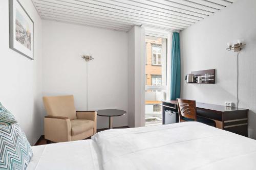 a bedroom with a bed and a desk and a chair at Havly Hotell in Stavanger