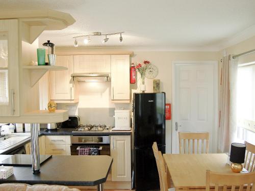 a kitchen with a black refrigerator and a table at Rosewater Lodge in Saint Teath