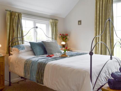 a bedroom with a large bed with white sheets and blue pillows at Holly Cottage in Pett