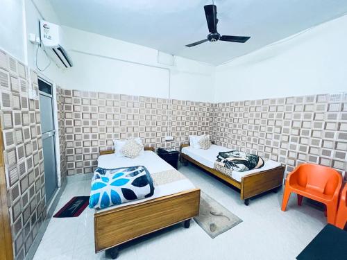 Habitación con 2 camas y silla naranja en HOTEL RAJGIR INTERNATIONAL, en Rajgir