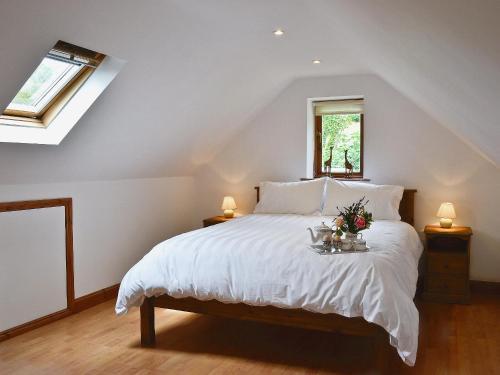 a bedroom with a white bed with flowers on it at Little Shelvin Farm Cottage in Luppitt