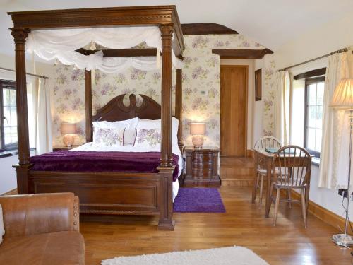 a bedroom with a canopy bed with a purple bedspread at Quantock Hideaway in Nether Stowey