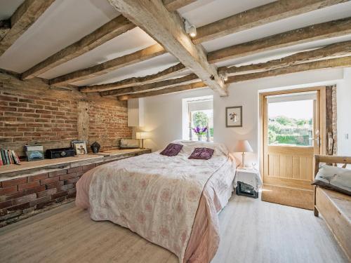 een slaapkamer met een bed en een bakstenen muur bij The West Barn in Hanley Castle