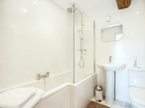 a white bathroom with a shower and a sink at The West Barn in Hanley Castle