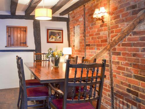 a dining room with a brick wall and a table and chairs at Tudor Cottage in Romsey