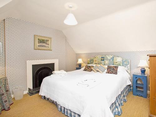 a bedroom with a white bed and a fireplace at Gardeners Cottage-uxt in Corsock