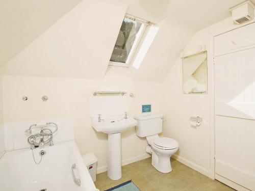 a white bathroom with a toilet and a sink at Gardeners Cottage-uxt in Corsock