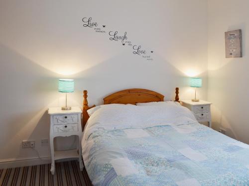 a bedroom with a bed with two night stands and two lamps at Beach Walk Cottage in Scarborough