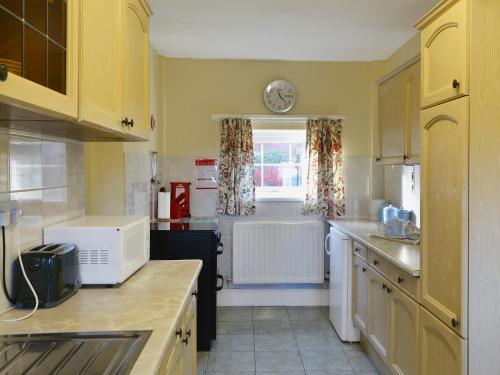 a kitchen with yellow cabinets and a clock on the wall at The Coach House in Wetheral