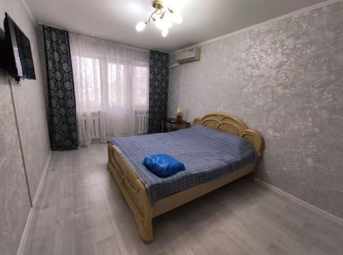 a bedroom with a bed with a blue pillow on it at Уютная квартира 2 Бесконтактное заселение круглосуточно in Oral