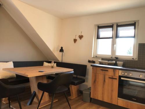 eine Küche mit einem Holztisch sowie einem Tisch und Stühlen in der Unterkunft Appartement Sonnenstrahl Ferienhaus Fuenf Sinne in Döbriach
