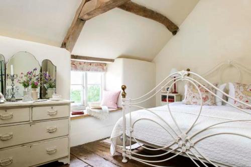 een slaapkamer met een wit bed, een dressoir en een spiegel bij The Old Bakehouse Cotswold Cottage in Stonesfield
