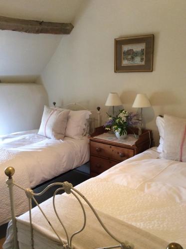 a bedroom with two beds and two tables with lamps at The Old Bakehouse Cotswold Cottage in Stonesfield