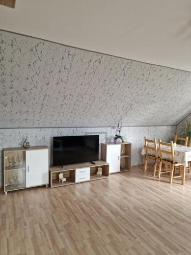 ein Wohnzimmer mit einem TV, einem Tisch und Stühlen in der Unterkunft Apartment da Elisa in Rietheim-Weilheim