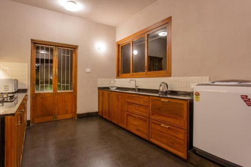 uma cozinha com armários de madeira e um frigorífico branco em Fully AC 3BDHK villa with Jacuzzi pool and courtyard em Porvorim