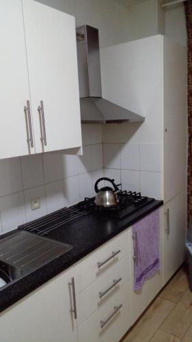 una cucina con armadi bianchi e un bollitore per il tè sul piano cottura di SUPPER Family room a Bruxelles