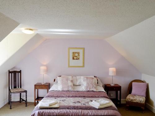 a bedroom with a bed with two chairs and two lamps at Kilpatrick Farm House in Pinmore