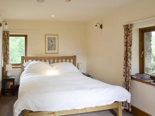 a bedroom with a large bed with white sheets at The Coach House in Corney