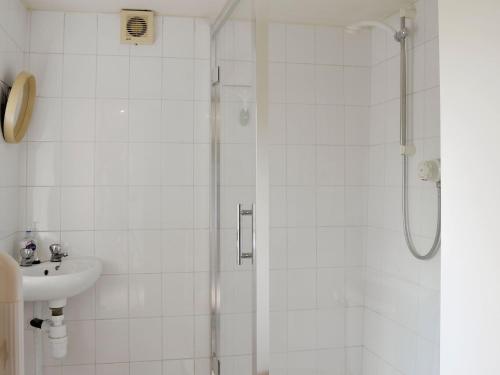 a white bathroom with a shower and a sink at The Coach House in Corney