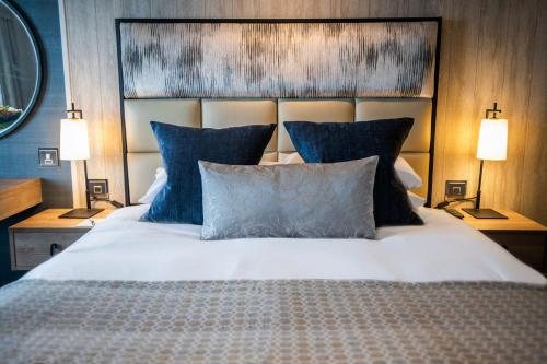 a bedroom with a large bed with blue pillows at Seamill Hydro Hotel in Seamill