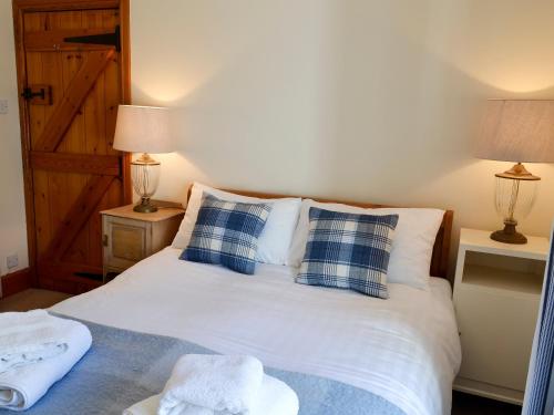 a bedroom with a bed with blue and white pillows at Limpet Cottage in Boulmer