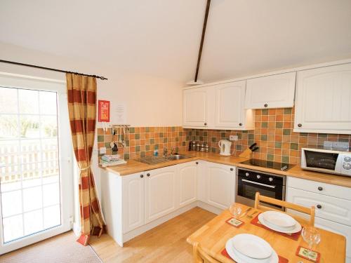 cocina con armarios blancos y mesa de madera en Moorhen Cottage - E3750 en Leverton