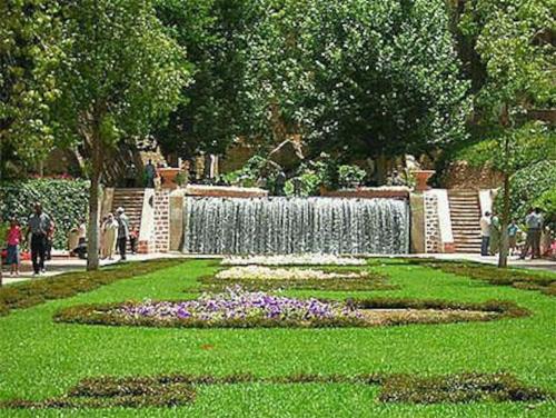 una fuente en un parque con flores en la hierba en cosy appartement au Centre de la ville avec WIFI, en Beni Mellal