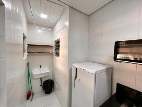 a small white bathroom with a sink and a refrigerator at Villagio Valentina in São Sebastião
