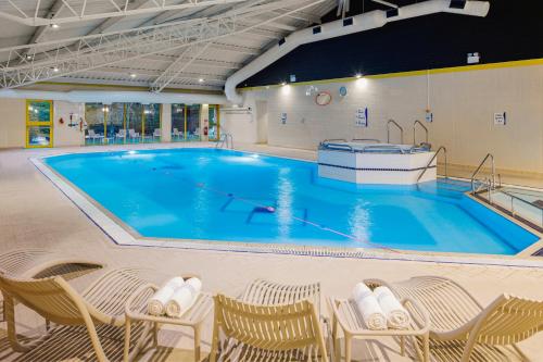 uma grande piscina com cadeiras e uma grande piscina em Holiday Inn Southampton Eastleigh, an IHG Hotel em Eastleigh