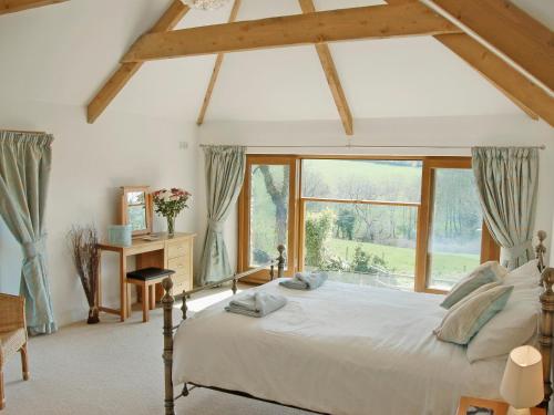 a bedroom with a large bed and a window at Polmear Barn in Camelford