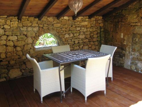 une table et des chaises dans une pièce avec un mur en pierre dans l'établissement Landhaus mit Pool Petite Mombette, à Cénac-et-Saint-Julien
