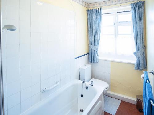 a white bathroom with a tub and a window at Columbine Cottage in Ross on Wye